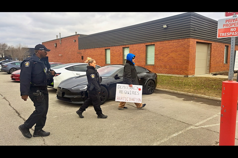 Anti-Tesla protester escorted off the car company's dealership lot by Halton Regional Police on March 25. 