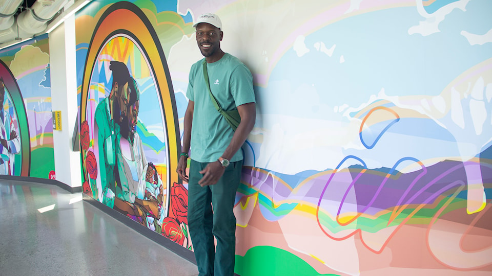 artist-phillip-saunders-stands-in-front-of-mural