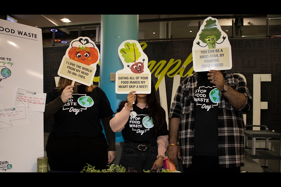 Members from Humber Food hold up placards to emphasize the importance of reducing food waste.