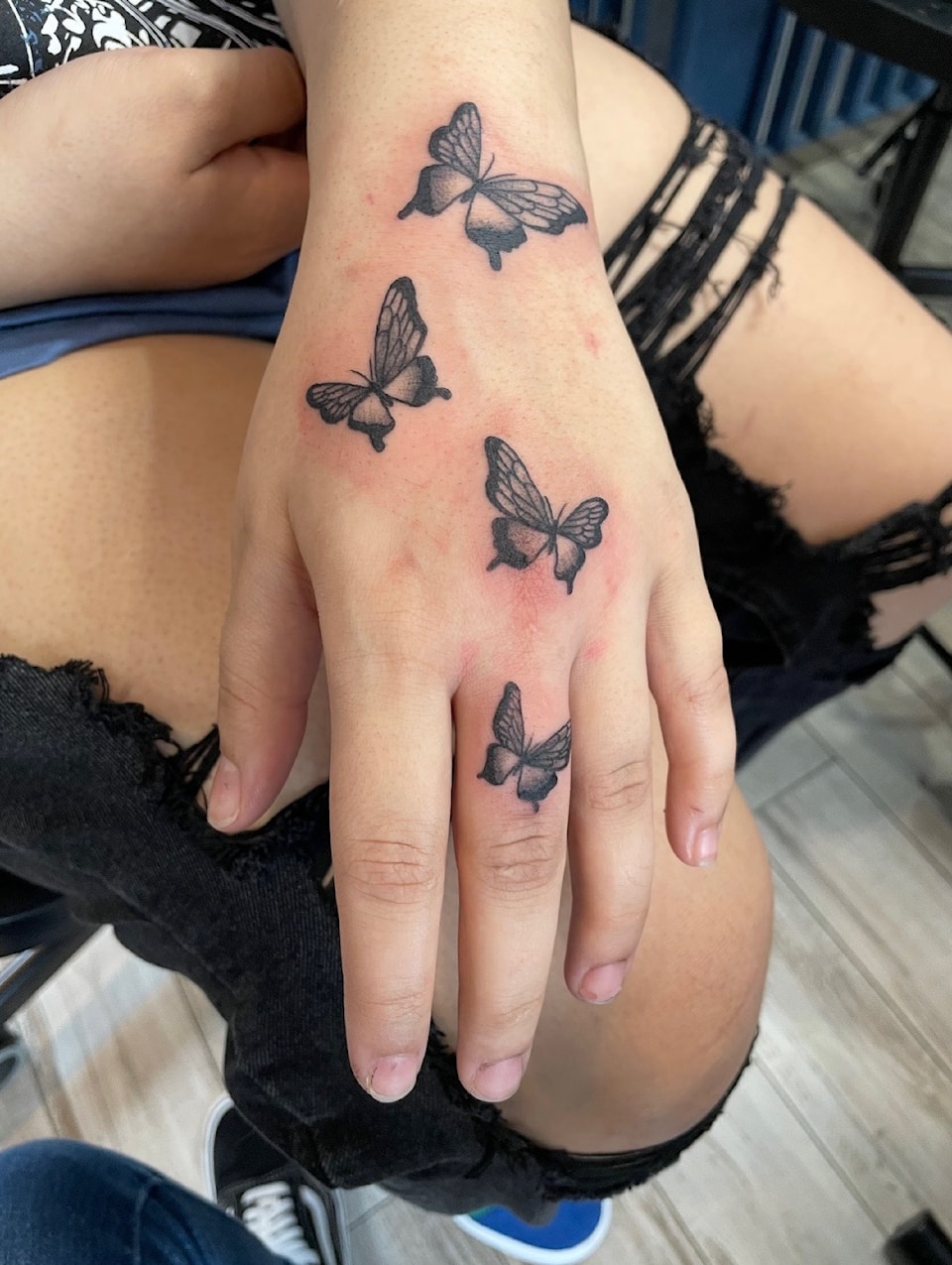 A photo of a woman displaying her new butter fly tattoos on her hand and wrist, that she got in memory of her father after his passing