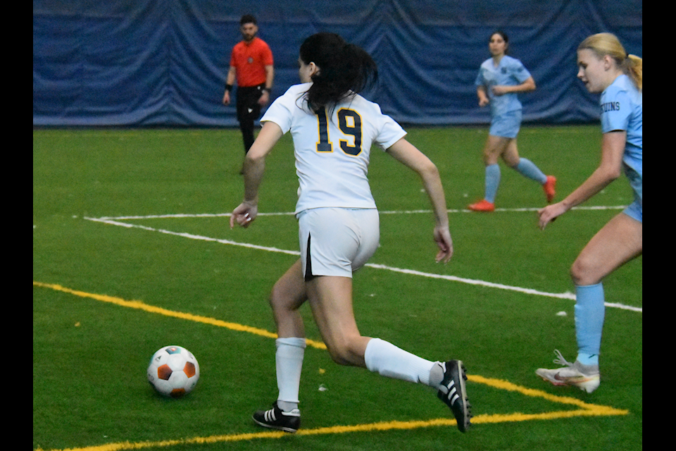 Humber's midfielder Isabella Chiappetta (19) before kicking at goal as Sheridan defender Brookelynn Litwiller (12) tries to catch her up during their last OCAA regional championship match.