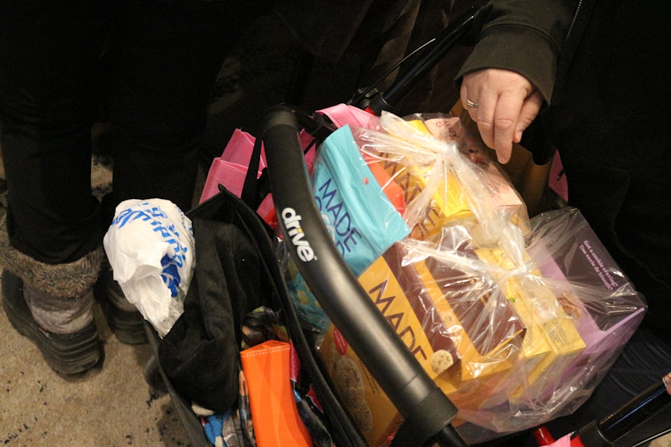 An attendee with a cart and a bag full of assorted tea that were available for sale at the festival held at the Toronto Reference Library. 
